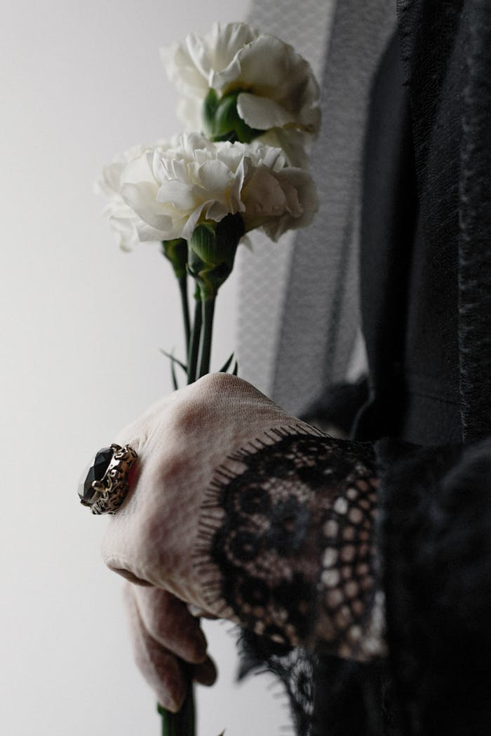 Mastering the First Impression: Your intriguing post title goes here Artistic close-up of a hand holding white carnations, symbolizing elegance and loss.